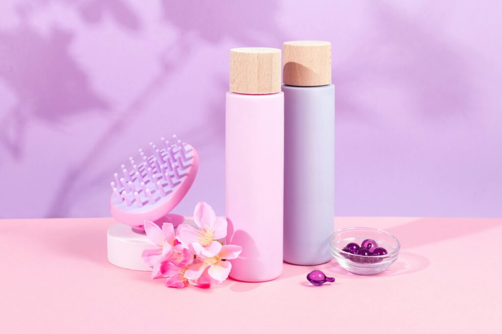 Mockup shampoo and conditioner bottles with shampoo brush and hair vitamins on vibrant pink backgrou